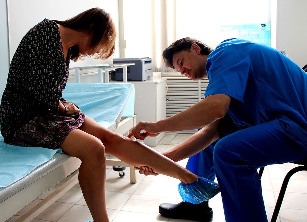 the doctor examines the leg with varicose veins